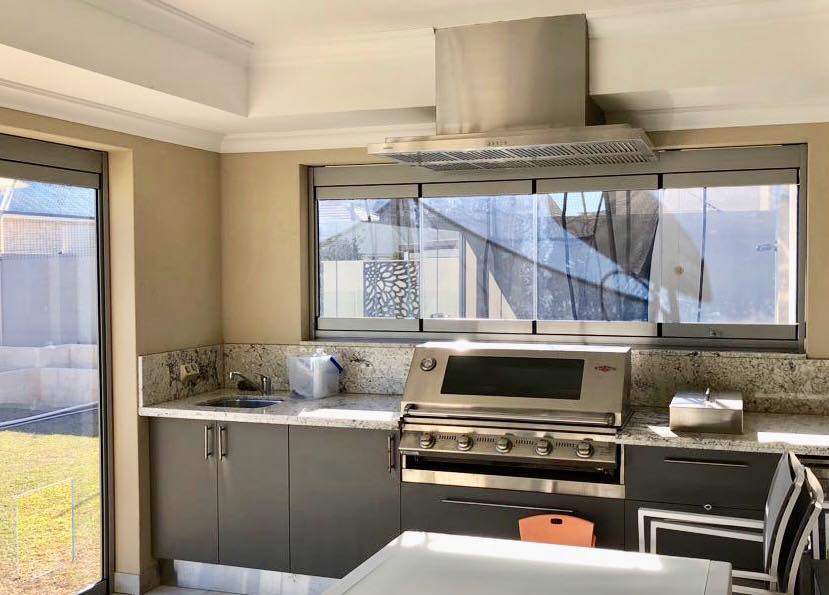 Image of a traditional servery window in a restaurant kitchen. Chef preparing food in background. Servery area with overhanging heat lamps in foreground.