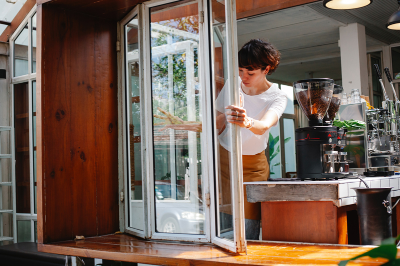 Cafe staff member opening a bifold servery window. Getting ready for morning coffee run. 