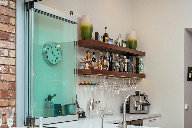 An new servery window from Clear Edge Glass. Modern servery, with well stocked bar in background.